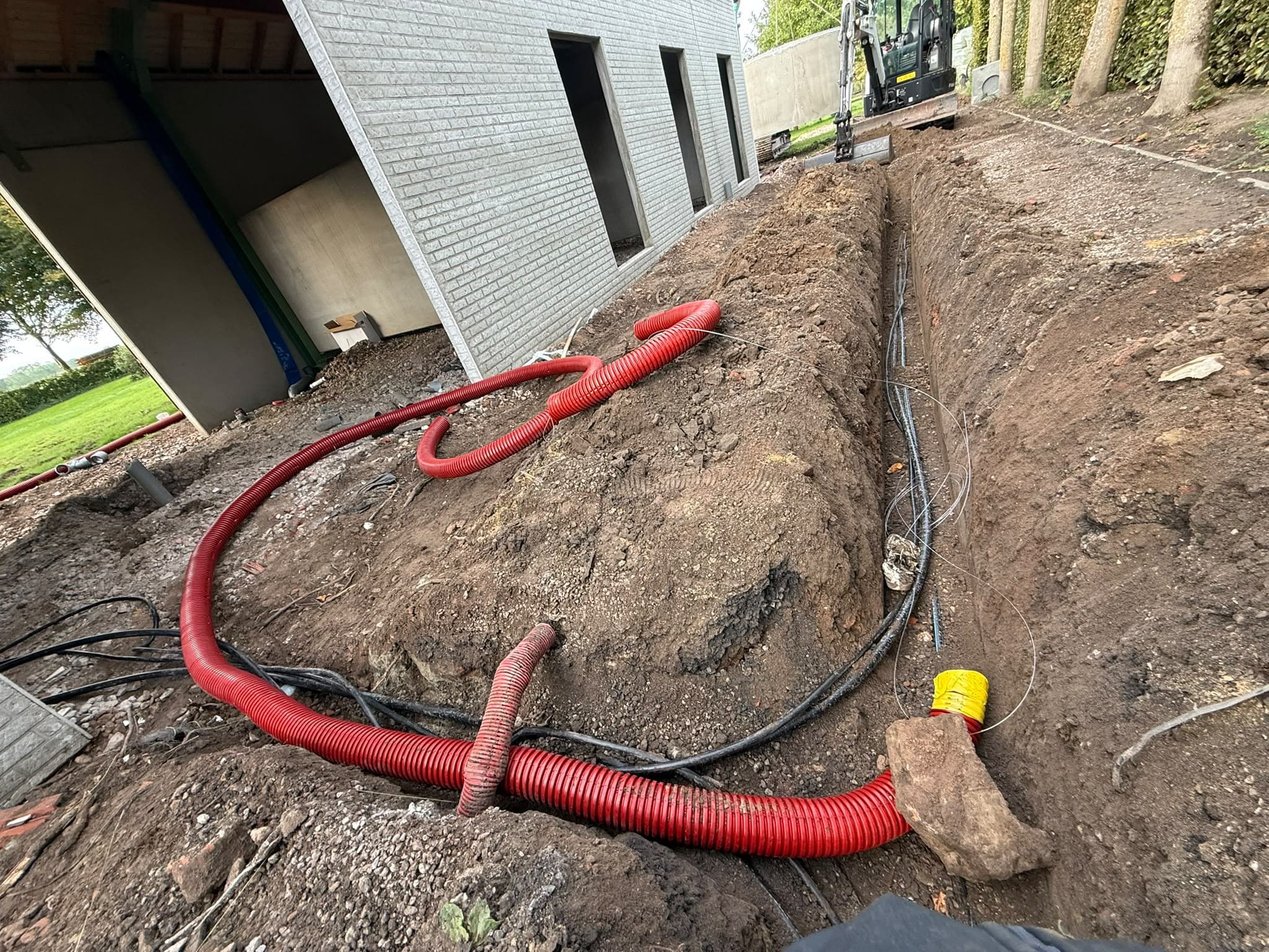 Sleuf met kabels en rode mantelbuizen