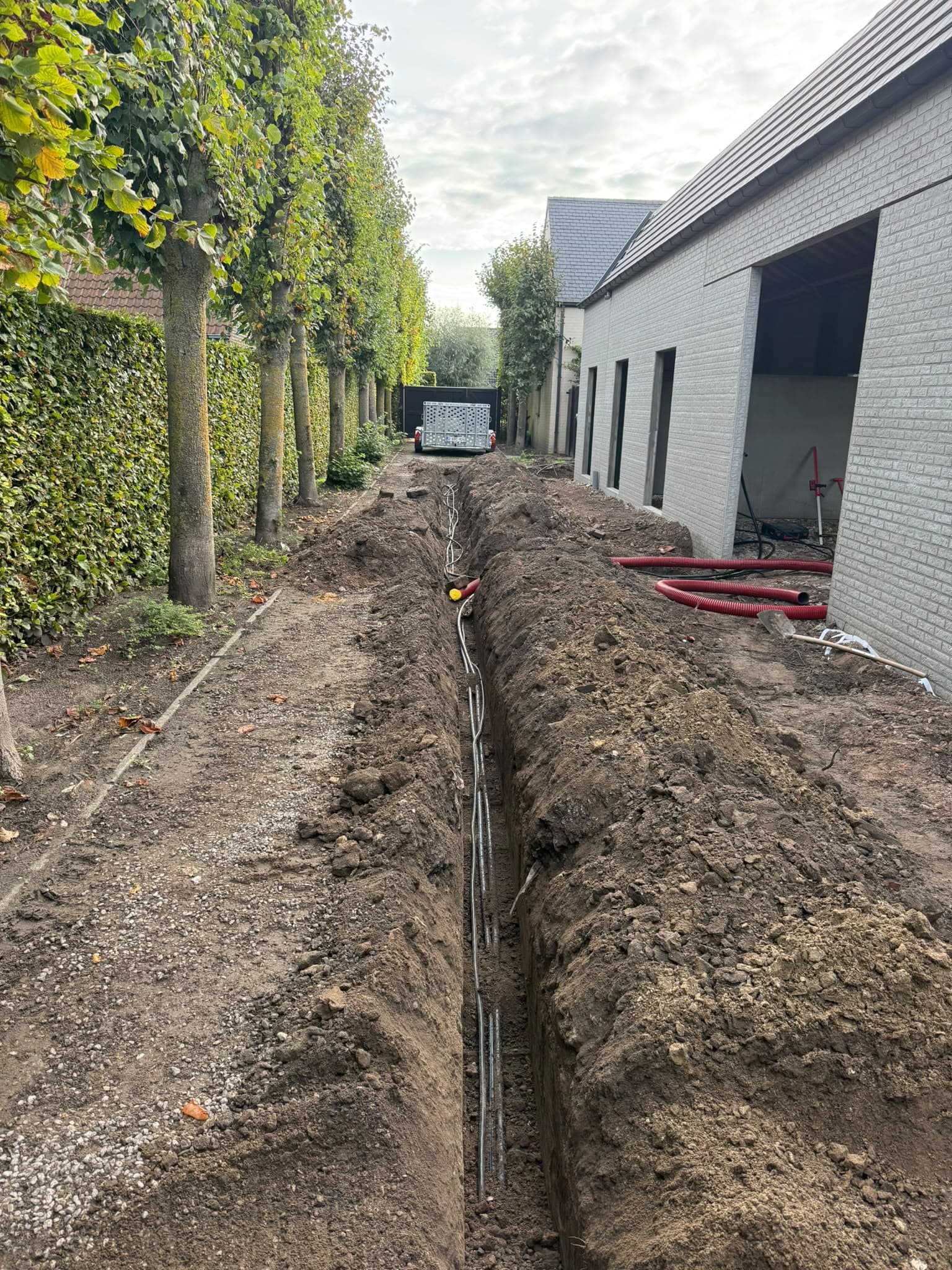 Lange sleuf voor leidingen langs een loods