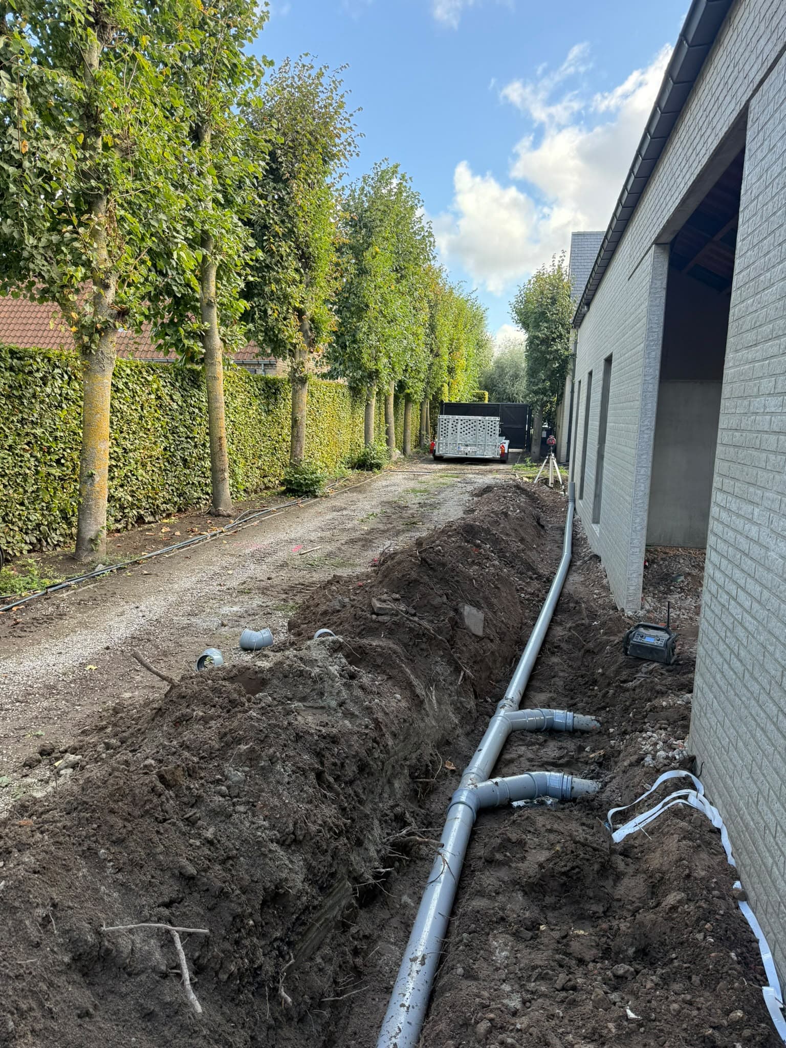 Afvoerleidingen in een sleuf langs een gebouw