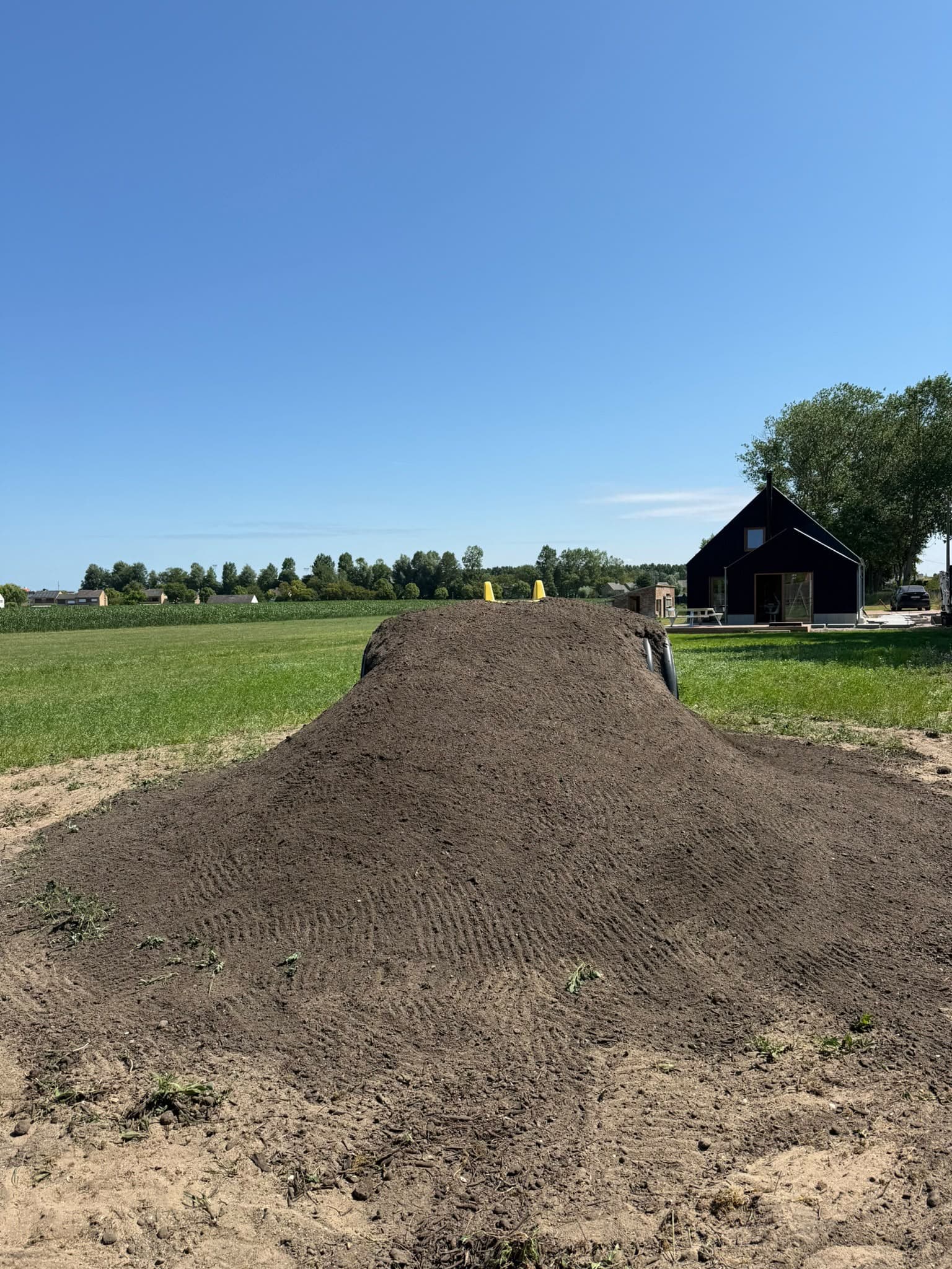 Grondwerk voor een speelheuvel in een tuin met weids uitzicht
