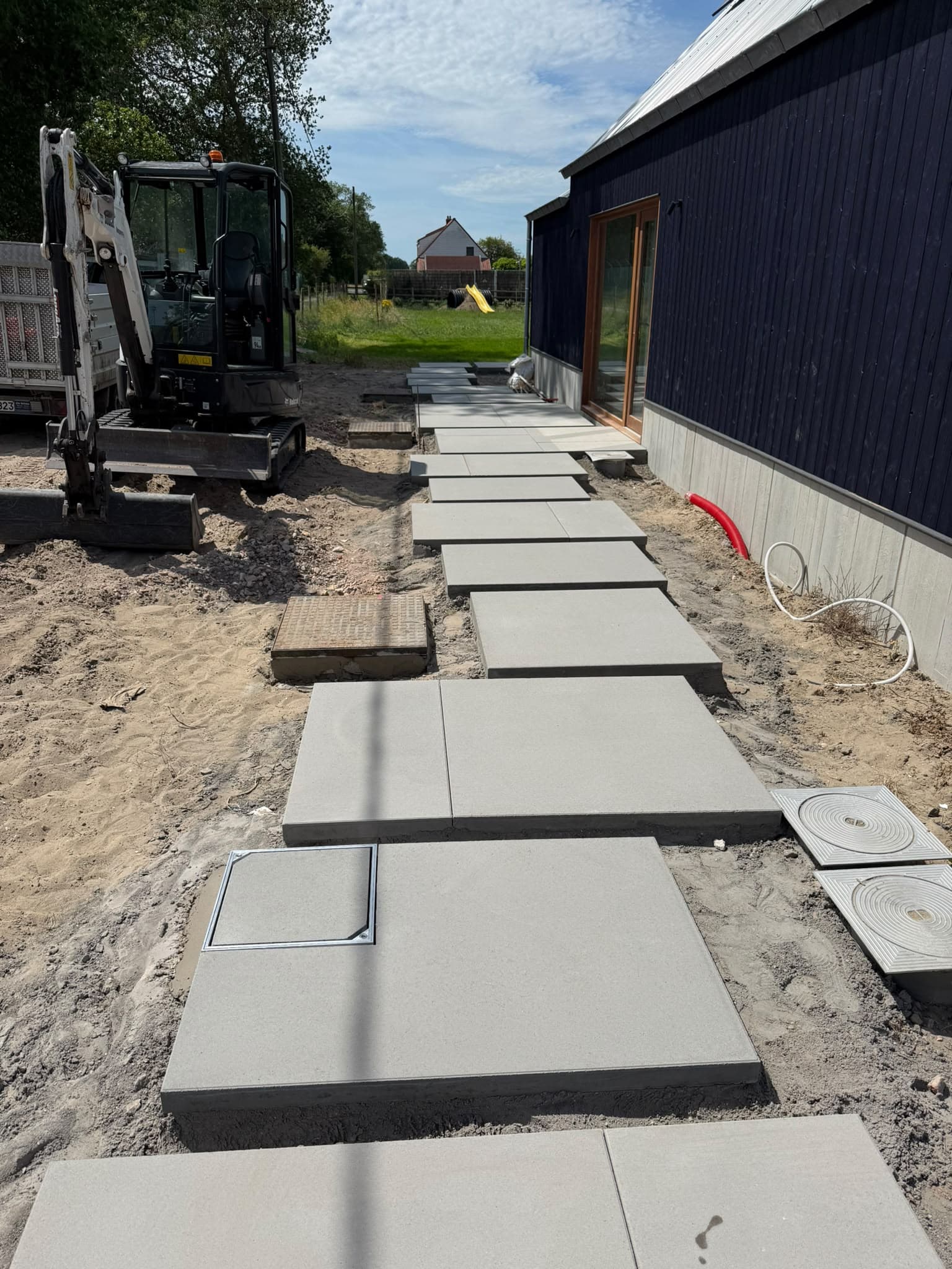 Aanleg van stapstenen in betonplaten, met minigraver