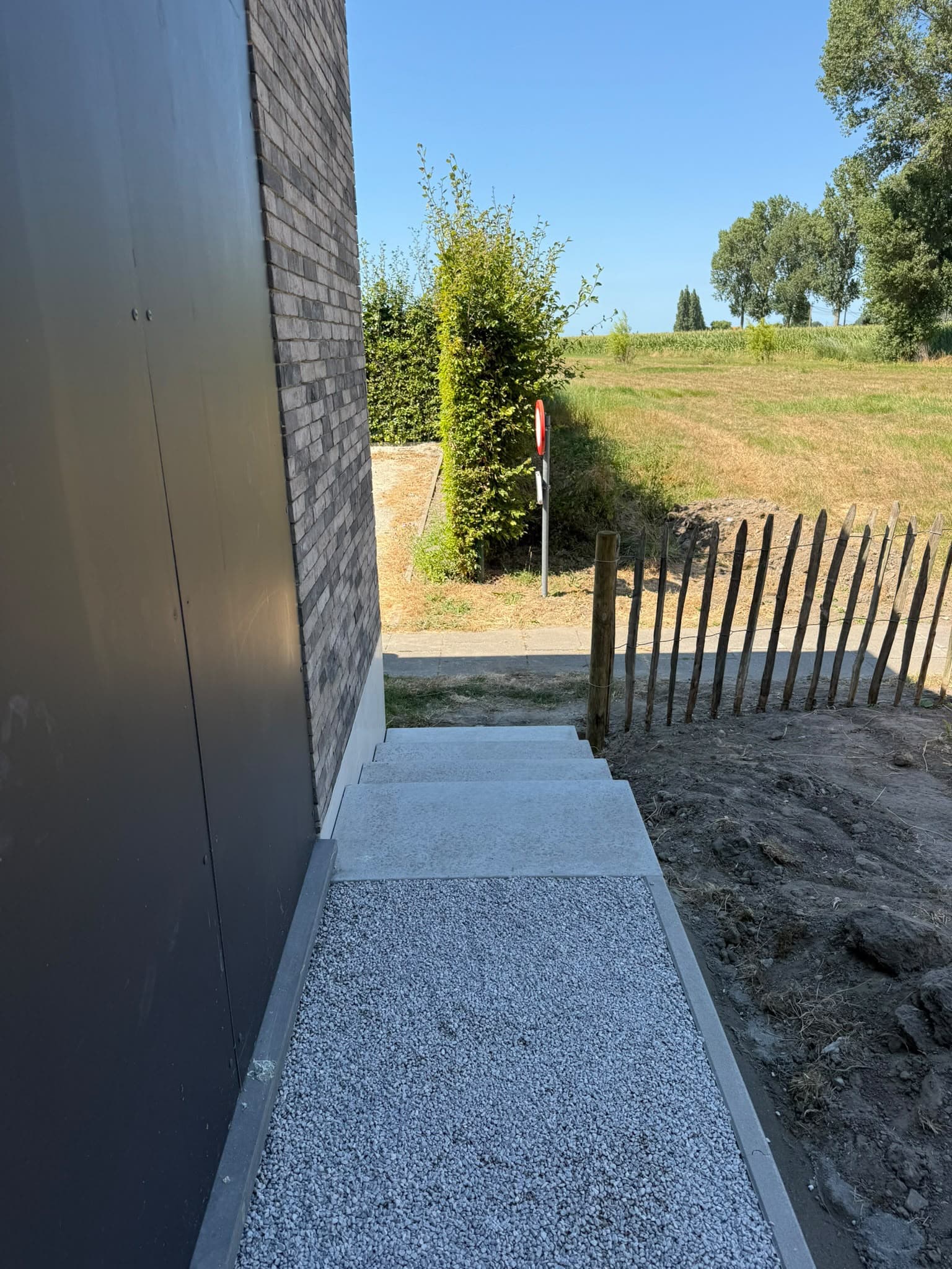 Tuinpad in grind en betontreden langs de gevel
